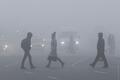 People cross a road through a heavy fog in Kiev