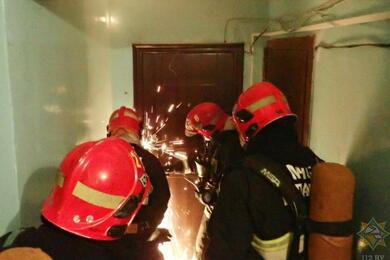 Сотрудники МЧС вскрывают дверь бензорезом. Снимок носит иллюстративный характер. Фото: МЧС Беларуси