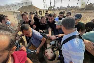 Палестинцы несут тело израильcкого военного, убитого боевиками ХАМАС во время нападения на границе Израиля и Газы, 7 октября 2023 года. Фото: Reuters