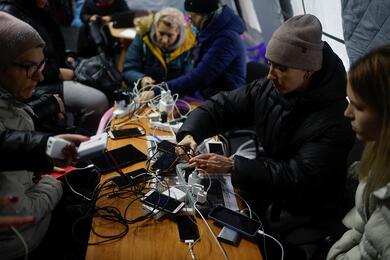 Местные жители заряжают свои устройства, подключаются к интернету и обогреваются в "пункте несокрушимости" в Киеве, Украина, 24 ноября 2022 года. Фото: Reuters