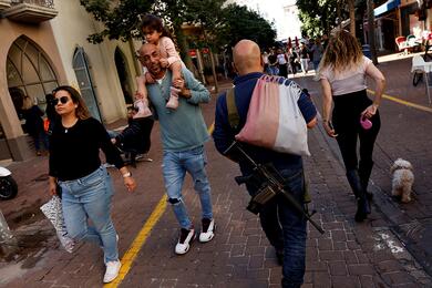 Люди проходят мимо мужчины с винтовкой в Тель-Авиве, Израиль, 9 февраля 2024 года. Фото: Reuters
