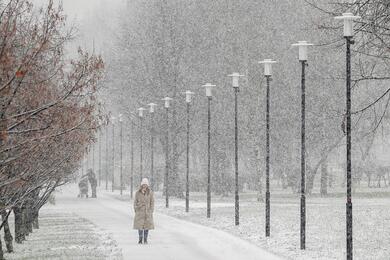 A pedestrian walks in a park during snowfall in Moscow