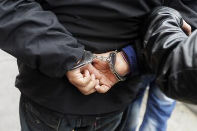 A man in handcuffs who was detained on suspicion of drug trafficking, is escorted by police outside the anti-drug unit of the National Police of Peru in Lima