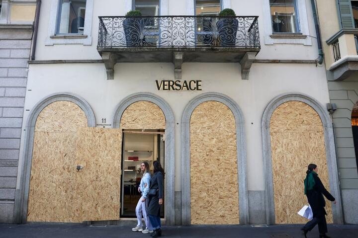 Люди проходят мимо заколоченного магазина Versace перед акцией протеста движения «17 октября» против роста стоимости жизни. Милан, Италия, 24 октября 2026 года. Фото: Reuters