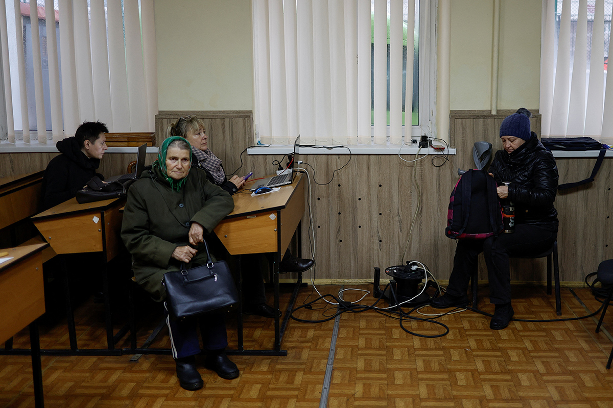 Местные жители заряжают свои устройства, подключаются к интернету и обогреваются в "пункте несокрушимости" в Киеве, Украина, 24 ноября 2022 года. Фото: Reuters